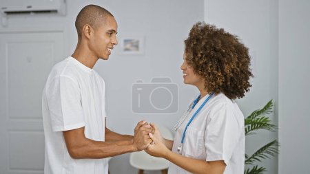 Médico y paciente disfrutan de una consulta médica reconfortante y segura, tomados de la mano en la bulliciosa clínica, trabajando hacia un futuro sonriente, saludable.