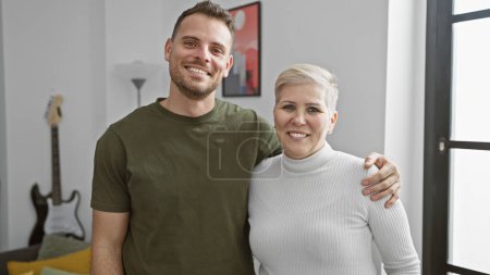 Foto de Una mujer feliz y el hombre abrazándose en una sala de estar moderna con una decoración elegante, exudando calidez y conexión familiar. - Imagen libre de derechos