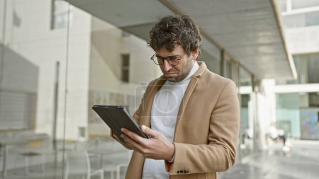 Handsome man with beard using tablet on urban city street
