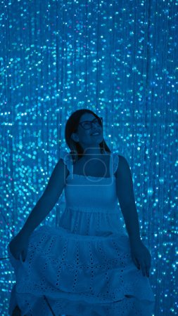Téléchargez les photos : Belle femme hispanique souriante expérimentant une exposition futuriste immersive au musée moderne lasers, lumières, innovation à leur meilleur! - en image libre de droit