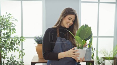 Photo for Smiling woman holding plant inside a bright flower shop, evoking a fresh indoor vibe - Royalty Free Image