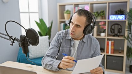 Hombre guapo trabajando con micrófono y auriculares en el estudio moderno de la estación de radio.