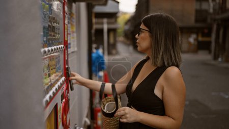 Schöne hispanische Frau mit Brille kauft am Straßenautomaten von Kyoto mit dem Handy und verbindet traditionellen Charme der Stadt mit modernem Komfort