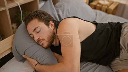Téléchargez les photos : Jeune homme hispanique couché sur le lit dormant dans la chambre - en image libre de droit