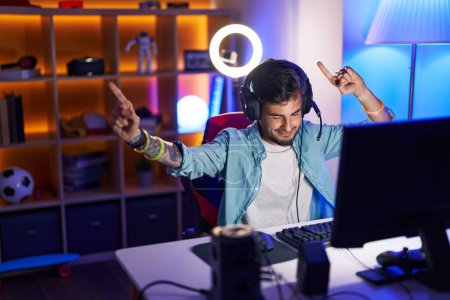 Photo for Young hispanic man streamer playing video game with winner expression at gaming room - Royalty Free Image