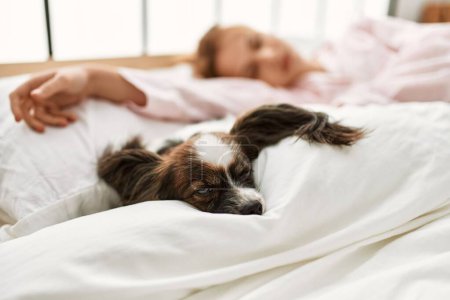 Junge Kaukasierin liegt mit Hund im Bett und schläft im Schlafzimmer