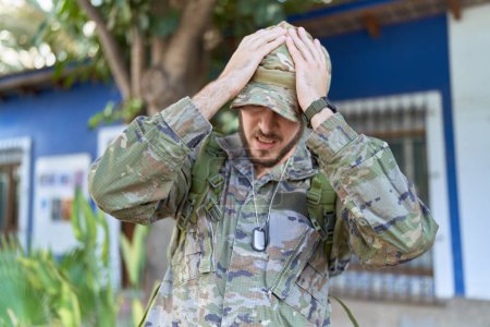 Photo for Young hispanic man wearing camouflage army uniform outdoors suffering from headache desperate and stressed because pain and migraine. hands on head. - Royalty Free Image