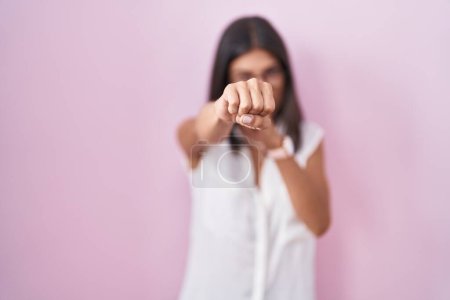 Téléchargez les photos : Brunette jeune femme debout sur fond rose portant des lunettes poing poing pour se battre, agressif et en colère attaque, menace et violence - en image libre de droit