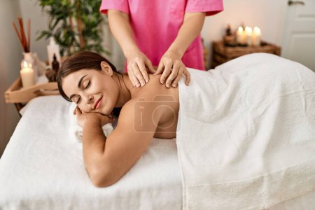 Photo for Young beautiful hispanic woman lying on table having back massage at beauty salon - Royalty Free Image