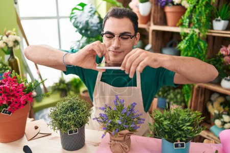 Photo for Young hispanic man florist make photo to lavender plant by smartphone at flower shop - Royalty Free Image