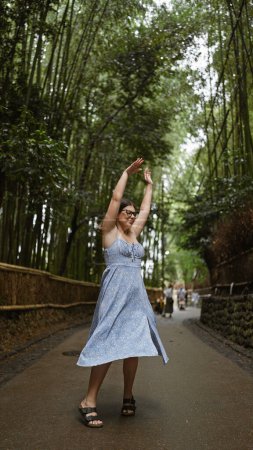 Cheerful hispanic woman in glasses spins around, her beautiful dress flowing in kyoto's enchanting bamboo forest