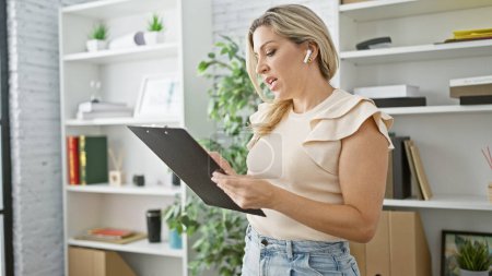 Young blonde woman business worker reading document having free hands call at the office