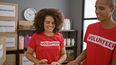 Photo for Man and woman volunteers smiling together, standing in unity at the charity center, embodying beautiful community activism - Royalty Free Image