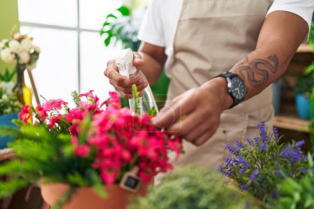 Téléchargez les photos : Jeune fleuriste latino-américain utilisant diffuseur travaillant à la boutique de fleurs - en image libre de droit