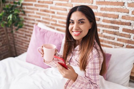 Téléchargez les photos : Jeune belle femme arabe utilisant smartphone boire du café dans la chambre - en image libre de droit