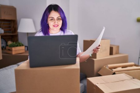 Photo for Young beautiful plus size woman using laptop reading document at new home - Royalty Free Image