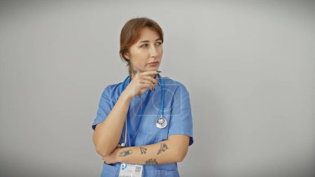 Téléchargez les photos : Femme caucasienne pensive dans des gommages bleus avec stéthoscope sur fond blanc. - en image libre de droit
