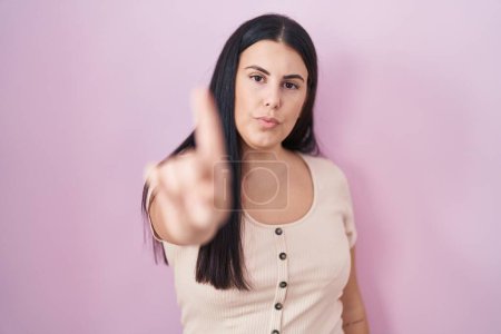 Téléchargez les photos : Young hispanic woman standing over pink background pointing with finger up and angry expression, showing no gesture - en image libre de droit