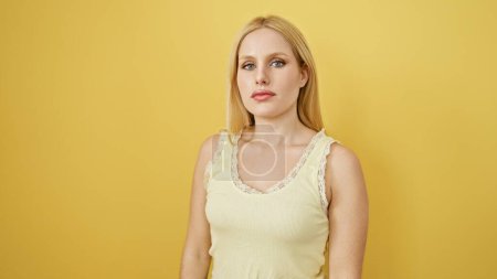 Photo for Portrait of a young, attractive blonde woman against a yellow isolated background, exuding confidence and beauty. - Royalty Free Image