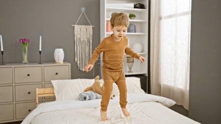 Photo for A joyful toddler boy jumps on a bed in a cozy modern bedroom, embodying childhood innocence. - Royalty Free Image