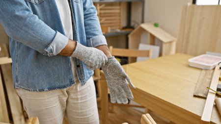 Photo for Crafty hands of a hispanic man, a glove-wearing carpenter immersed in woodwork at a professional carpentry workshop - Royalty Free Image