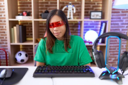 Foto de Mujer china de mediana edad que usa gafas de realidad virtual con la mano en el estómago porque las náuseas, la enfermedad dolorosa sensación de malestar. concepto ache. - Imagen libre de derechos