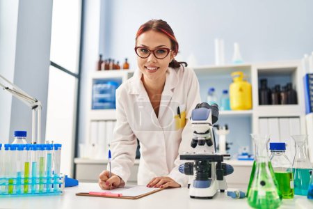 Photo for Young caucasian woman scientist writing report working at laboratory - Royalty Free Image