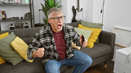 Foto de Hombre sorprendido viendo la televisión en una sala de estar moderna, expresando emoción - Imagen libre de derechos