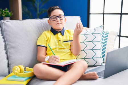 Photo for Young hispanic kid doing homework sitting on the sofa doing italian gesture with hand and fingers confident expression - Royalty Free Image