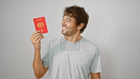 Téléchargez les photos : Jeune homme confiant, exsudant de la joie, arbore fièrement son passeport malais, isolé sur fond blanc - en image libre de droit