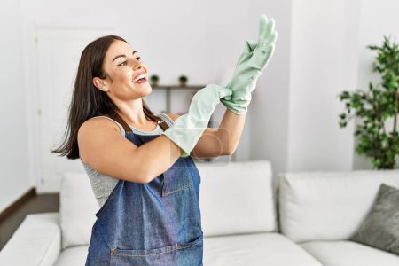 Photo for Young beautiful hispanic woman smiling confident wearing gloves at home - Royalty Free Image