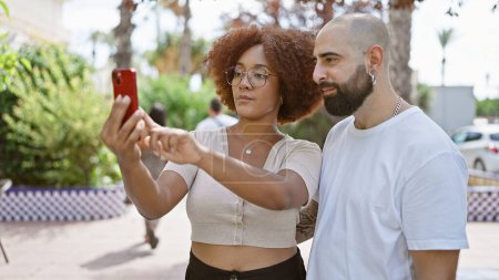 Téléchargez les photos : Beau couple faisant selfie rempli d'amour avec smartphone dans le parc ensoleillé - en image libre de droit