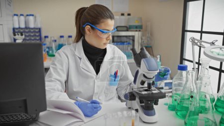 Téléchargez les photos : Femme scientifique hispanique analysant des échantillons en laboratoire, illustrant la recherche et les soins de santé. - en image libre de droit