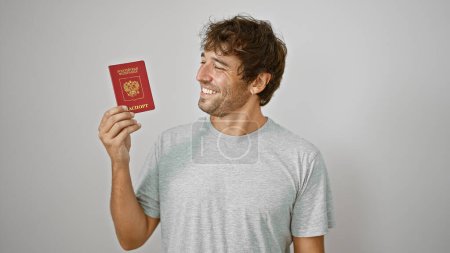 Foto de Joven rubio radiante, patriota de Rusia, tiene pasaporte con confianza sobre fondo blanco aislado, listo para disfrutar de su viaje de vacaciones - Imagen libre de derechos