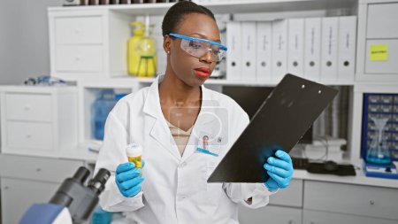 Photo for African american woman scientist is seriously reading a document about pills in a professional lab, amidst serious science research. - Royalty Free Image