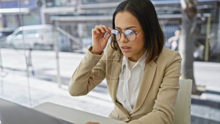 Téléchargez les photos : Femme hispanique professionnelle dans les lunettes de travail sur ordinateur portable au bureau moderne - en image libre de droit