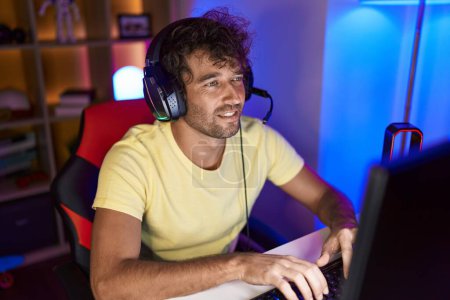 Foto de Joven streamer hispano jugando videojuegos usando computadora en la sala de juegos - Imagen libre de derechos