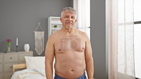Téléchargez les photos : Homme aux cheveux gris debout torse nu dans une chambre moderne - en image libre de droit