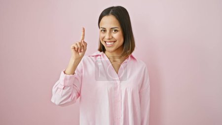 Photo for Smiling young hispanic woman pointing up, isolated on a pink background. - Royalty Free Image