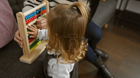 Foto de Una joven y una mujer juegan con un ábaco en una acogedora sala de estar, que representa los momentos familiares y educativos. - Imagen libre de derechos