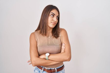 Téléchargez les photos : Jeune femme hispanique debout sur fond blanc regardant du côté avec les bras croisés convaincus et confiants - en image libre de droit