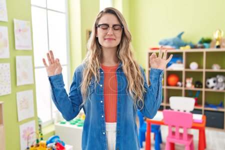 Photo for Young caucasian woman working as teacher at kindergarten relax and smiling with eyes closed doing meditation gesture with fingers. yoga concept. - Royalty Free Image