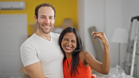 Téléchargez les photos : Beau couple debout ensemble tenant des clés à la nouvelle maison - en image libre de droit