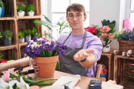 Photo for Caucasian blond man working at florist shop smiling cheerful offering palm hand giving assistance and acceptance. - Royalty Free Image