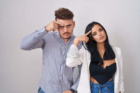 Photo for Young hispanic couple standing over white background pointing unhappy to pimple on forehead, ugly infection of blackhead. acne and skin problem - Royalty Free Image