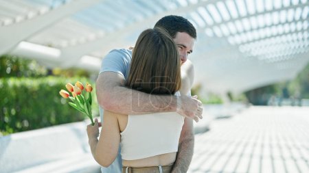 Téléchargez les photos : Beau couple surprise avec bouquet de fleurs se câlinant au parc - en image libre de droit