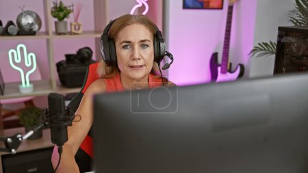 Photo for A middle-aged blonde woman engaged in gaming indoors at night, showcasing technology and leisure. - Royalty Free Image