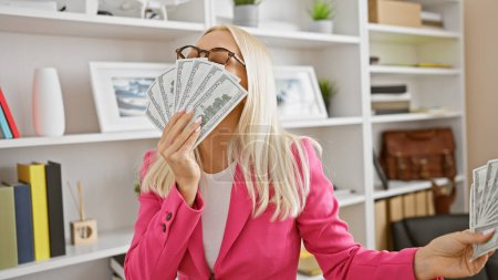 Téléchargez les photos : Belle femme d'affaires blonde embrasse dollars, portrait du succès au bureau - en image libre de droit