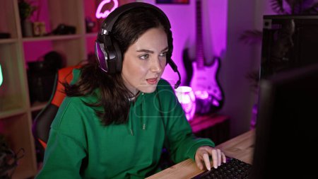 Caucasian woman gaming indoors at night, focused and enjoying her leisure time in a colorful room.