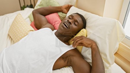Téléchargez les photos : Homme africain détendu dormant tranquillement dans sa chambre ensoleillée - en image libre de droit